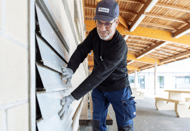 Photo d'un homme manipulant un clapet coupe-feu ou volet de désenfumage.
