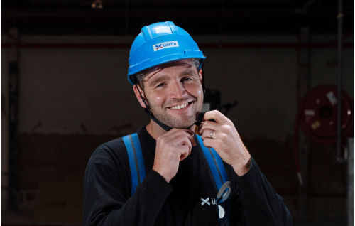 Photo d'un collaborateur souriant, accrochant son casque.