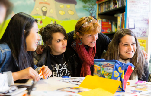 Photo d'une femme et de trois jeunes autour d'une table d'école.